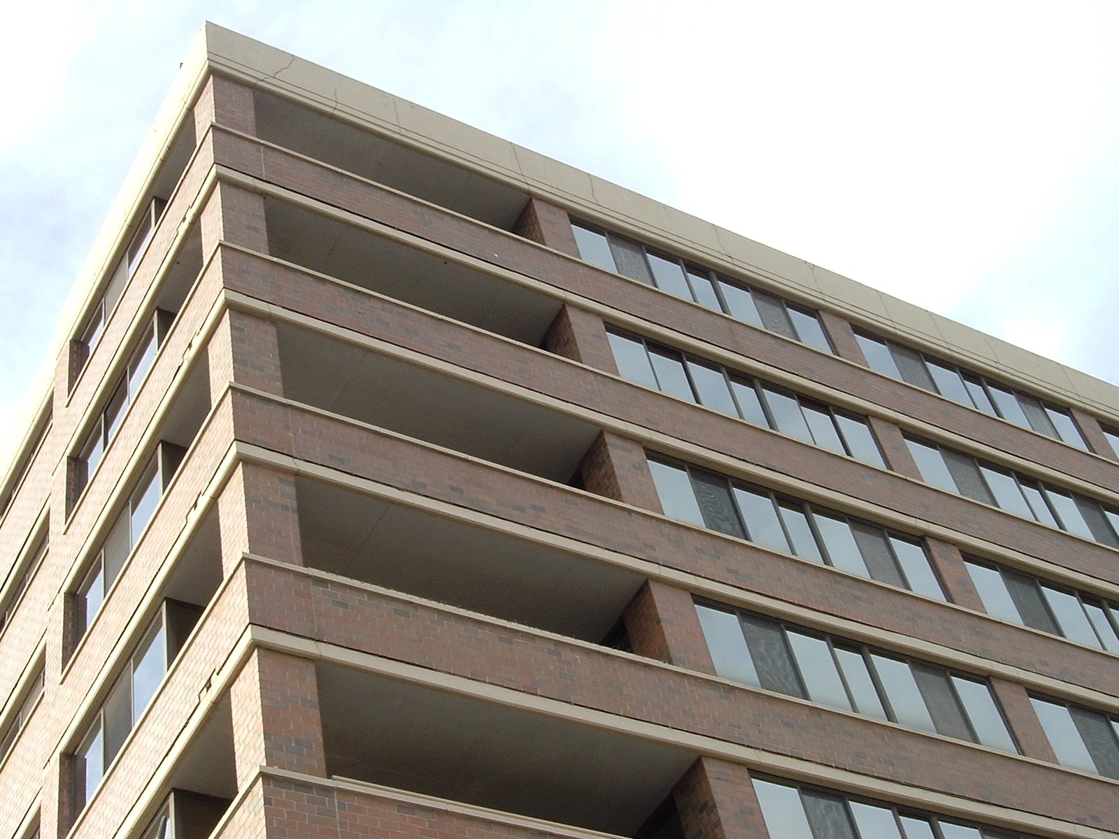 a tall brick building with windows and a stop sign attached to it