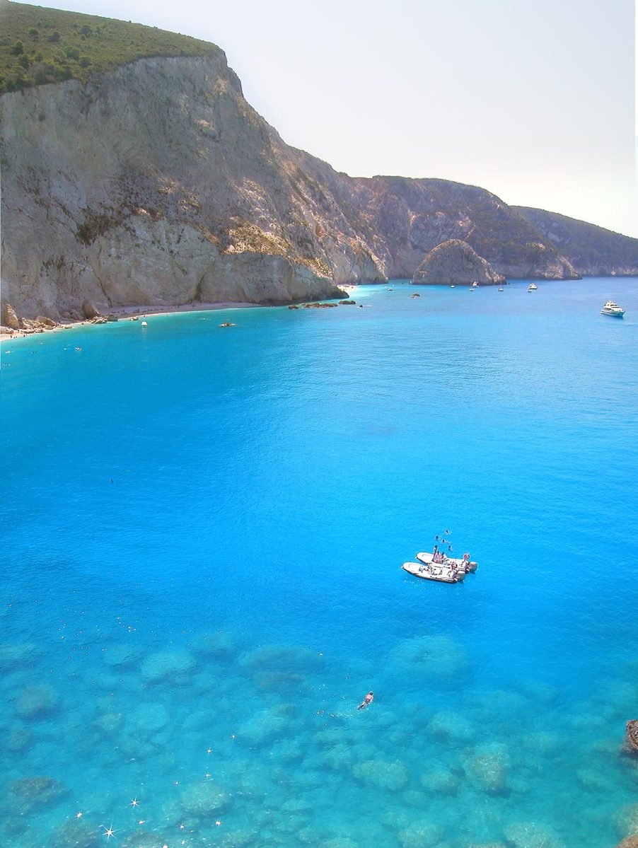 a view of a beach with clear blue waters and several boats