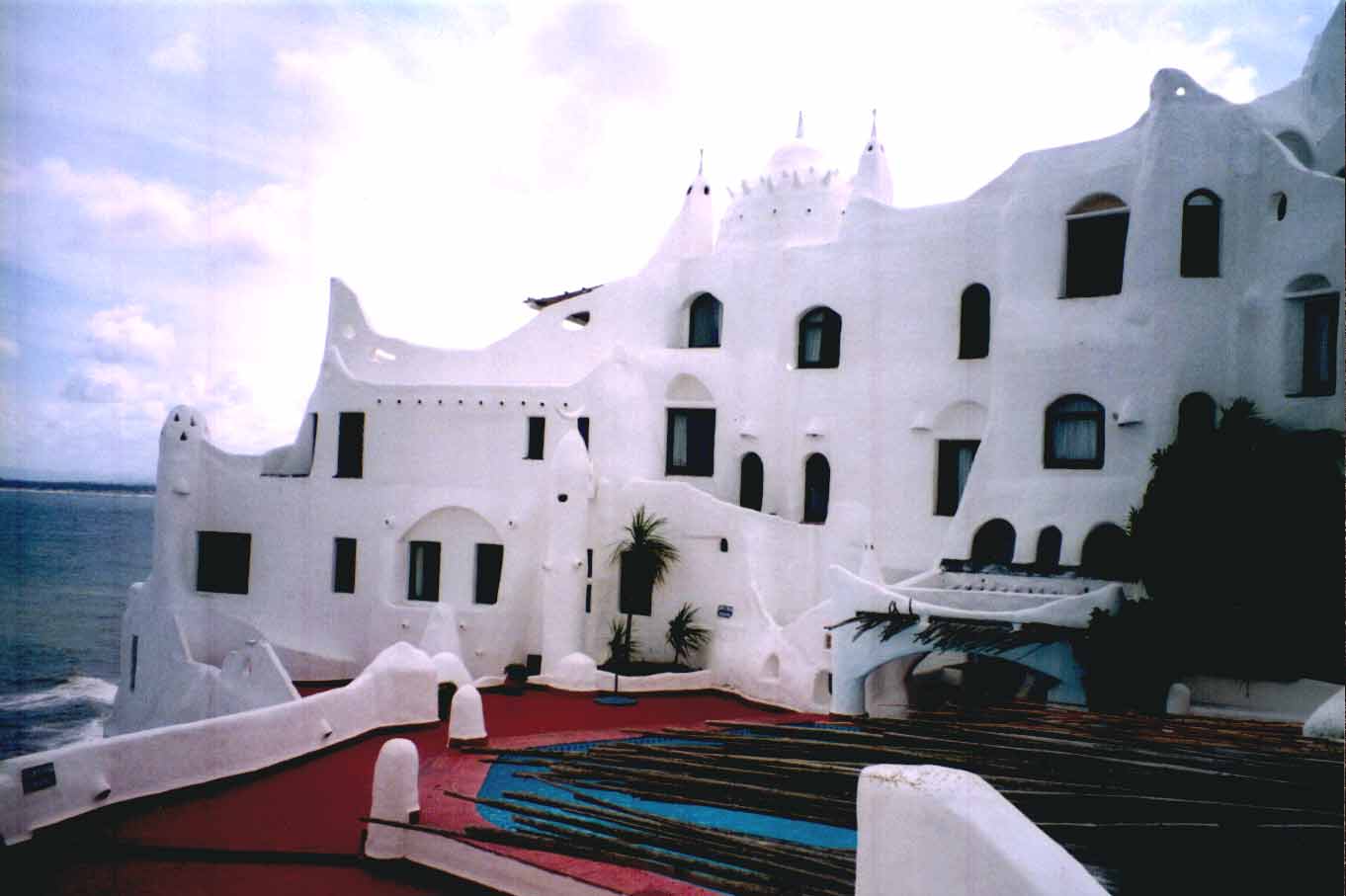 a white building on a beach has multiple windows