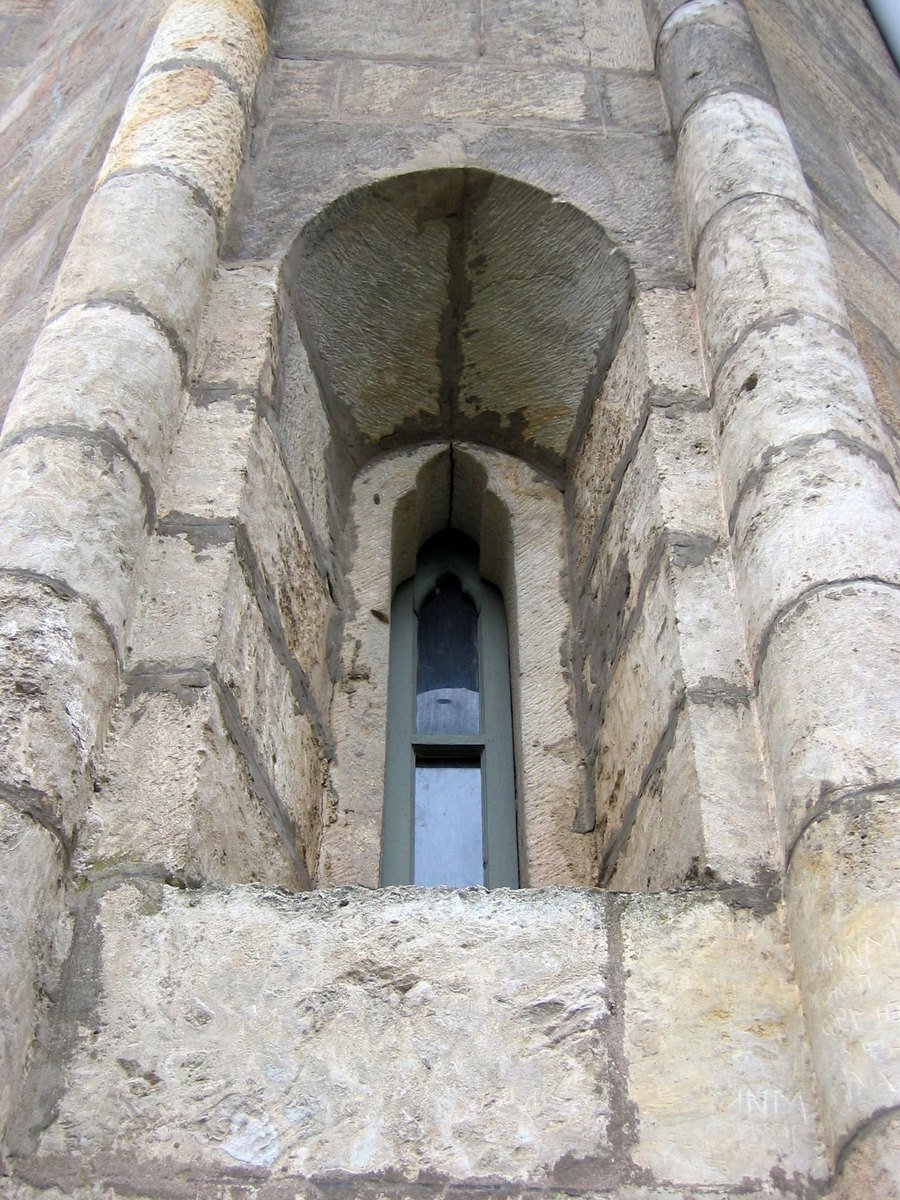 a tall stone building with a window in it