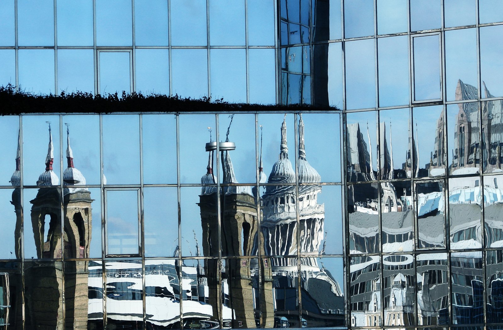 the reflection of buildings in the glass windows of a skyscr