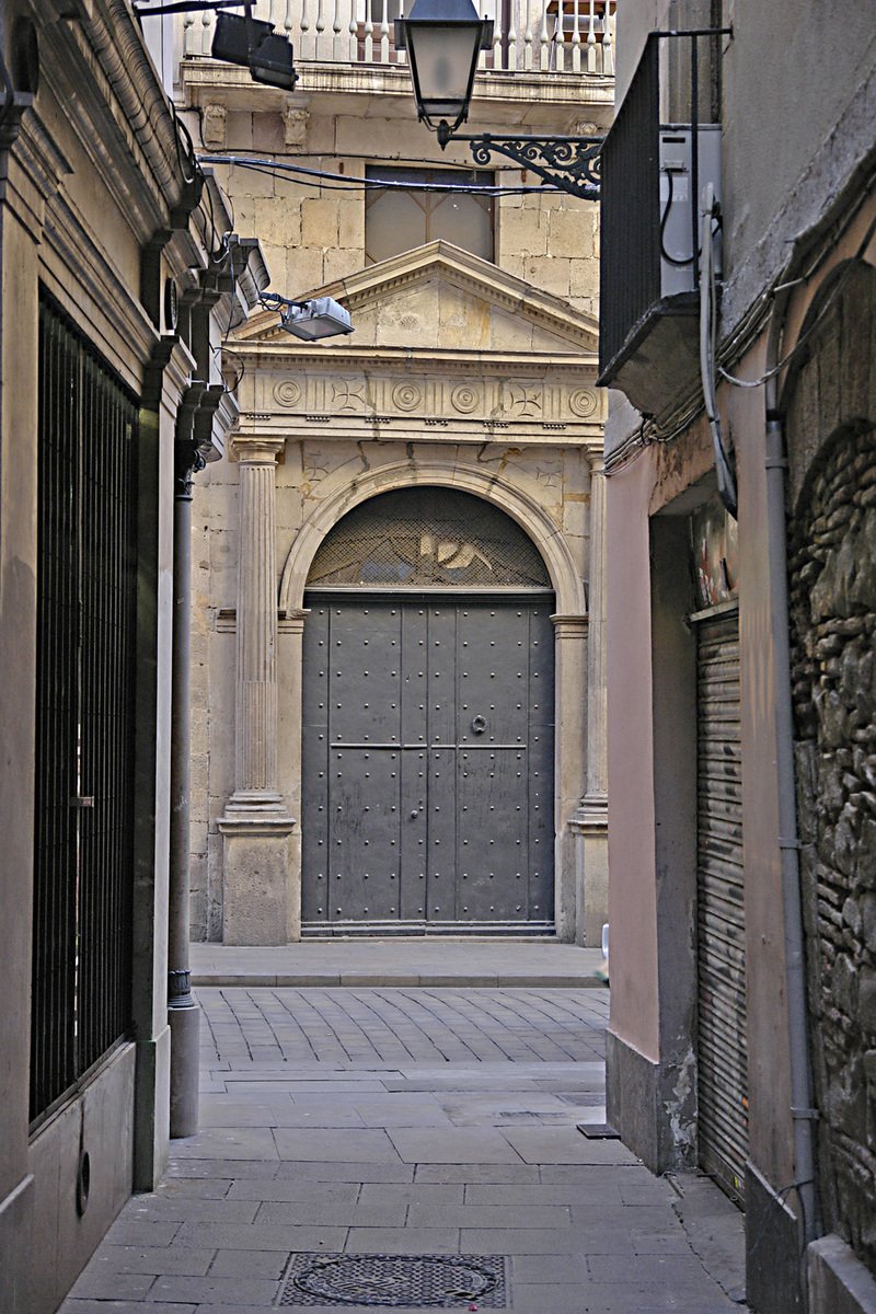 an old building with two large doors between it and another building with a light on top of it