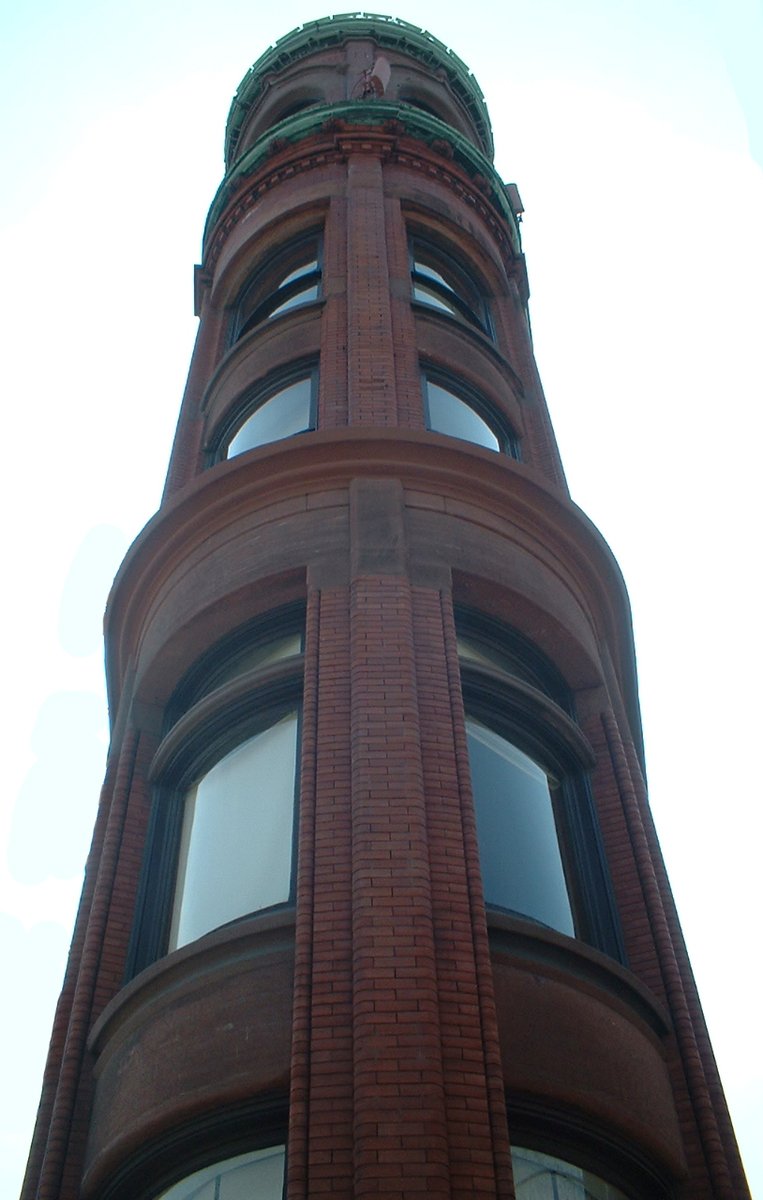 a tall red brick building with an outside clock