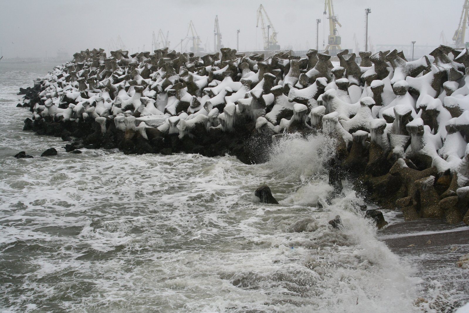 the waves are splashing up against the stone wall