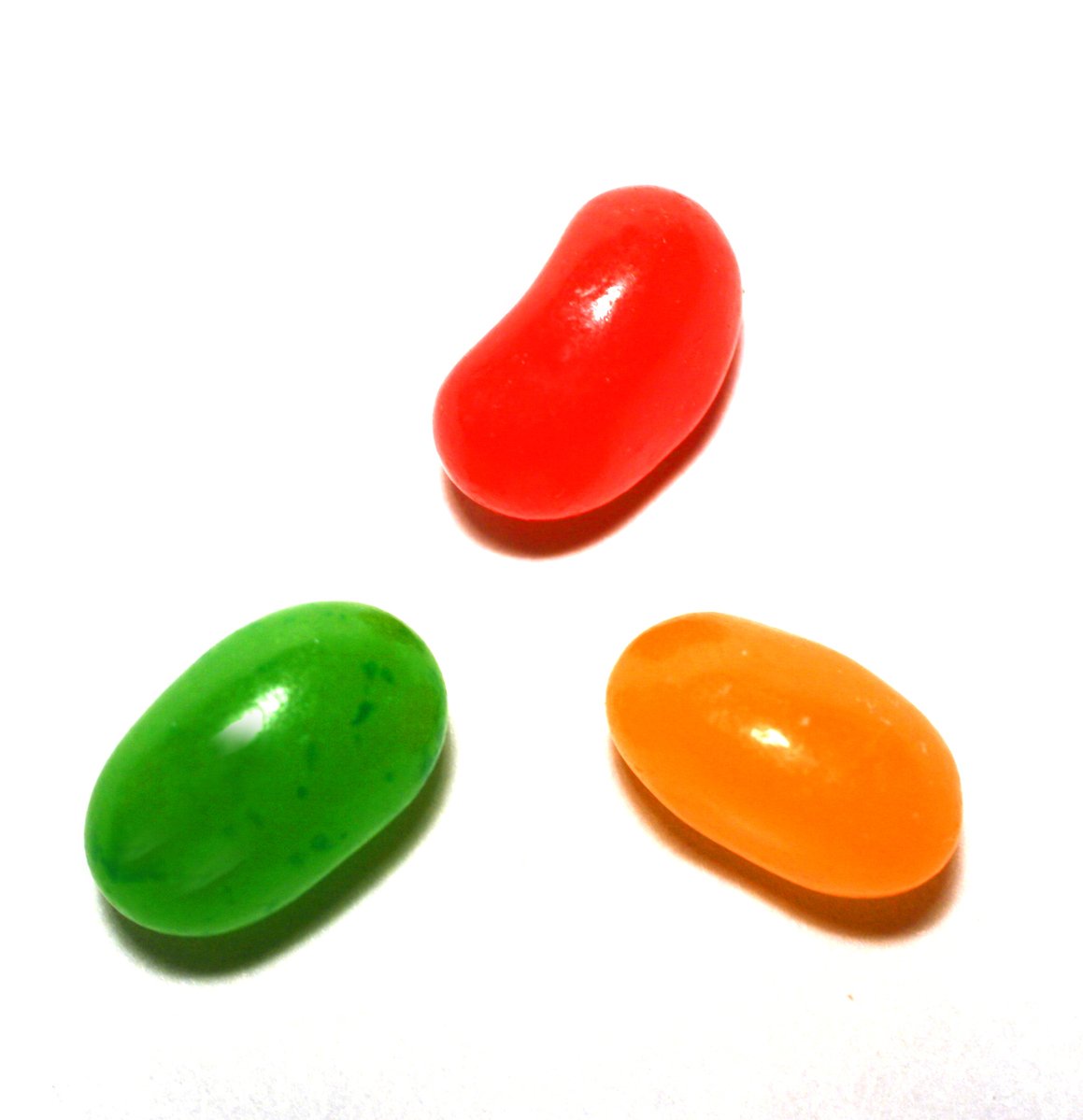 three different colors of jelly beans on a white surface