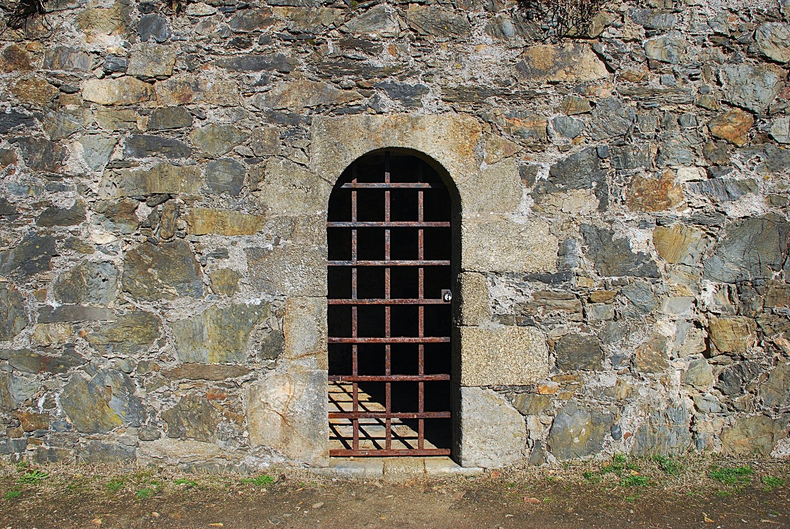 a small metal gate stands in front of a stone building