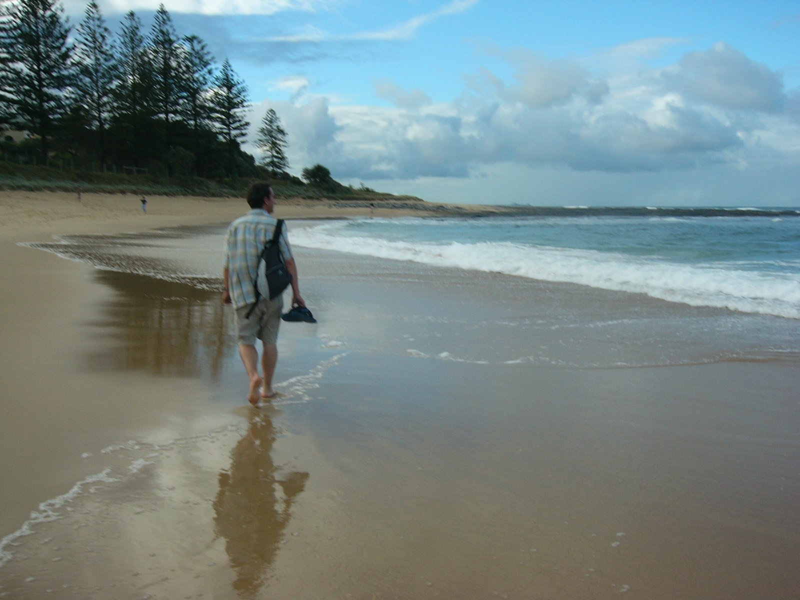 a man walking on the beach with a backpack