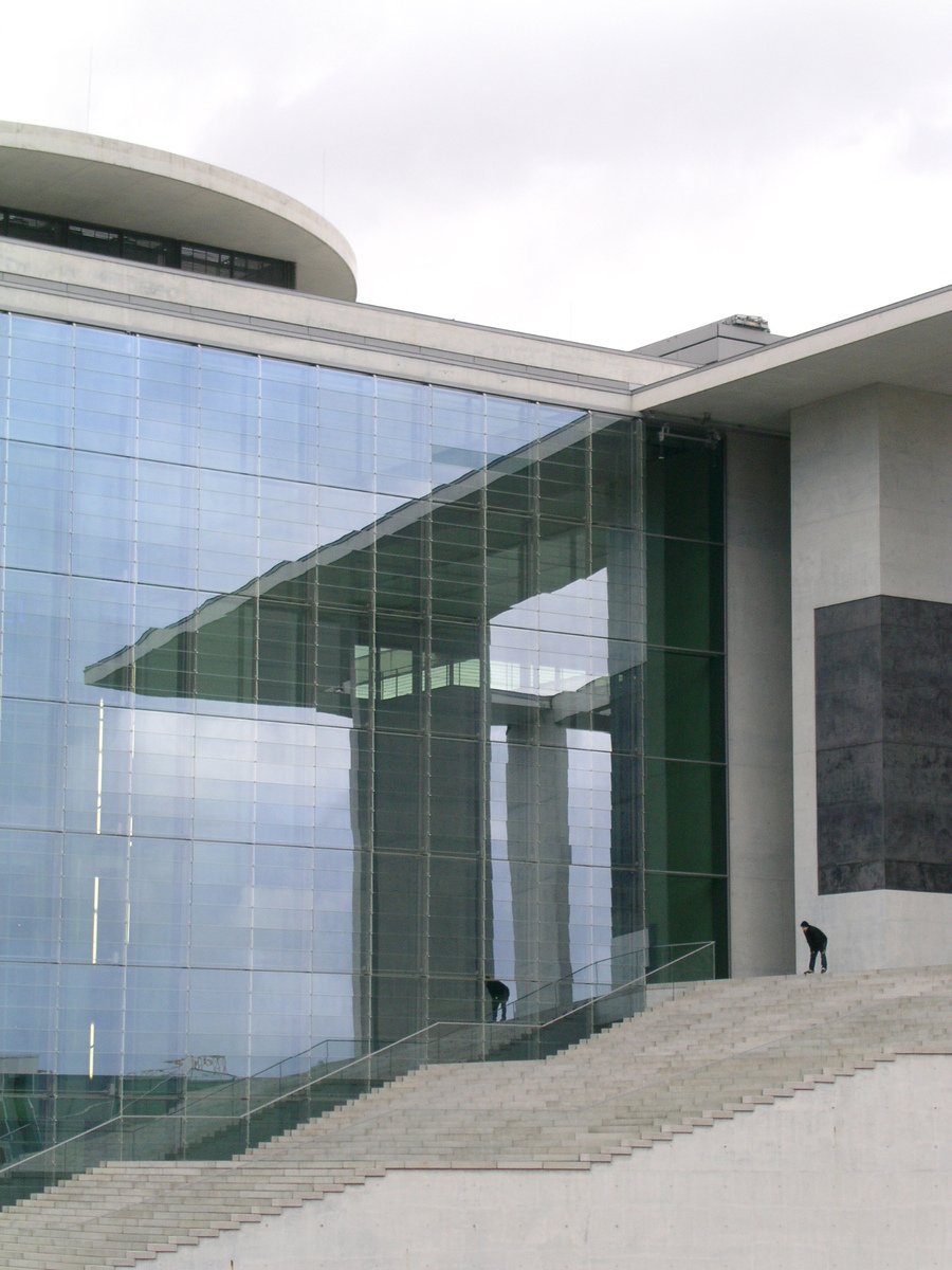a person walks on a stone step next to an elegant glass building