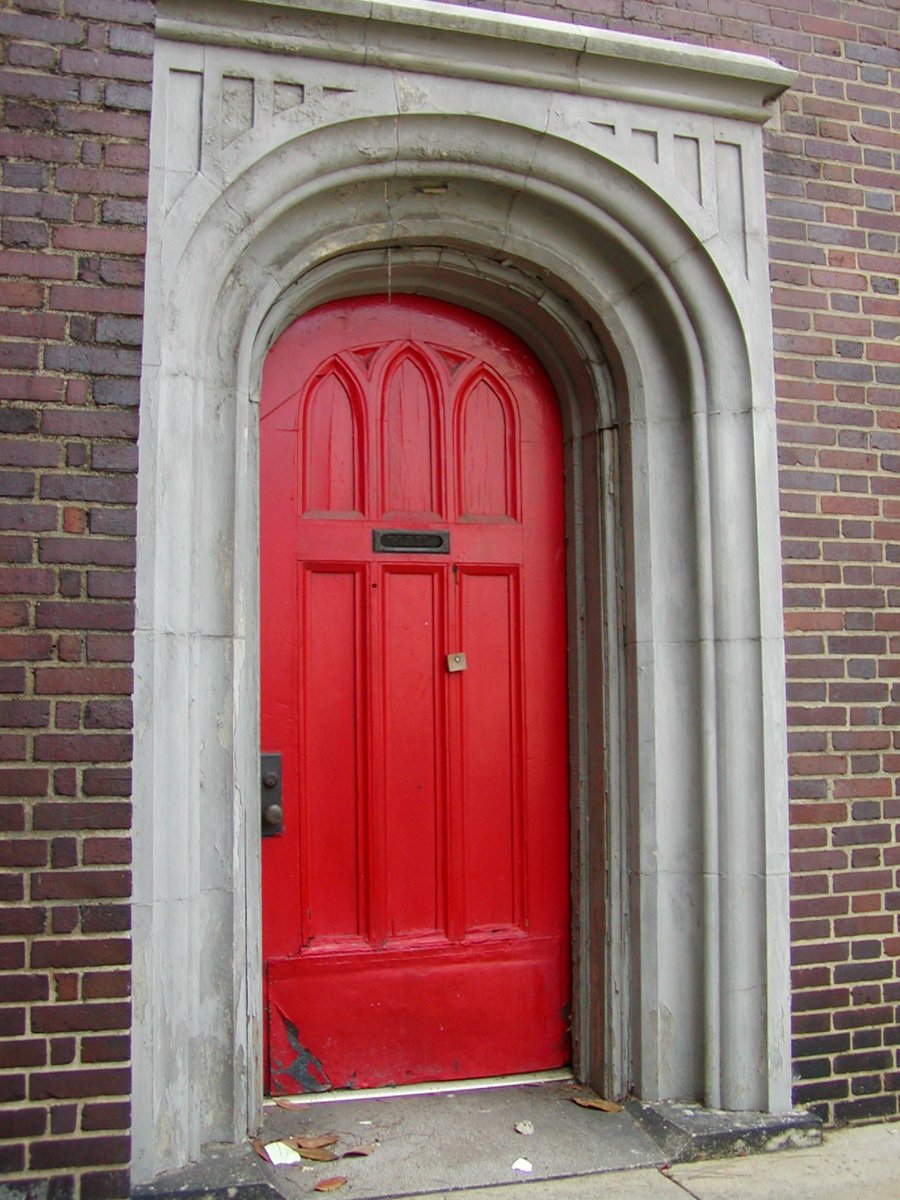 a red door sits in between two arches on the side of a building