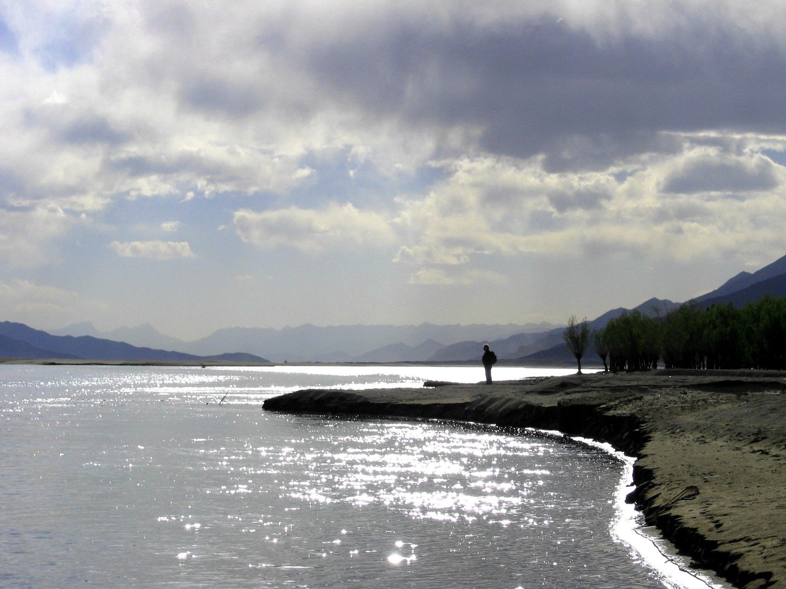 two people standing at the edge of a body of water