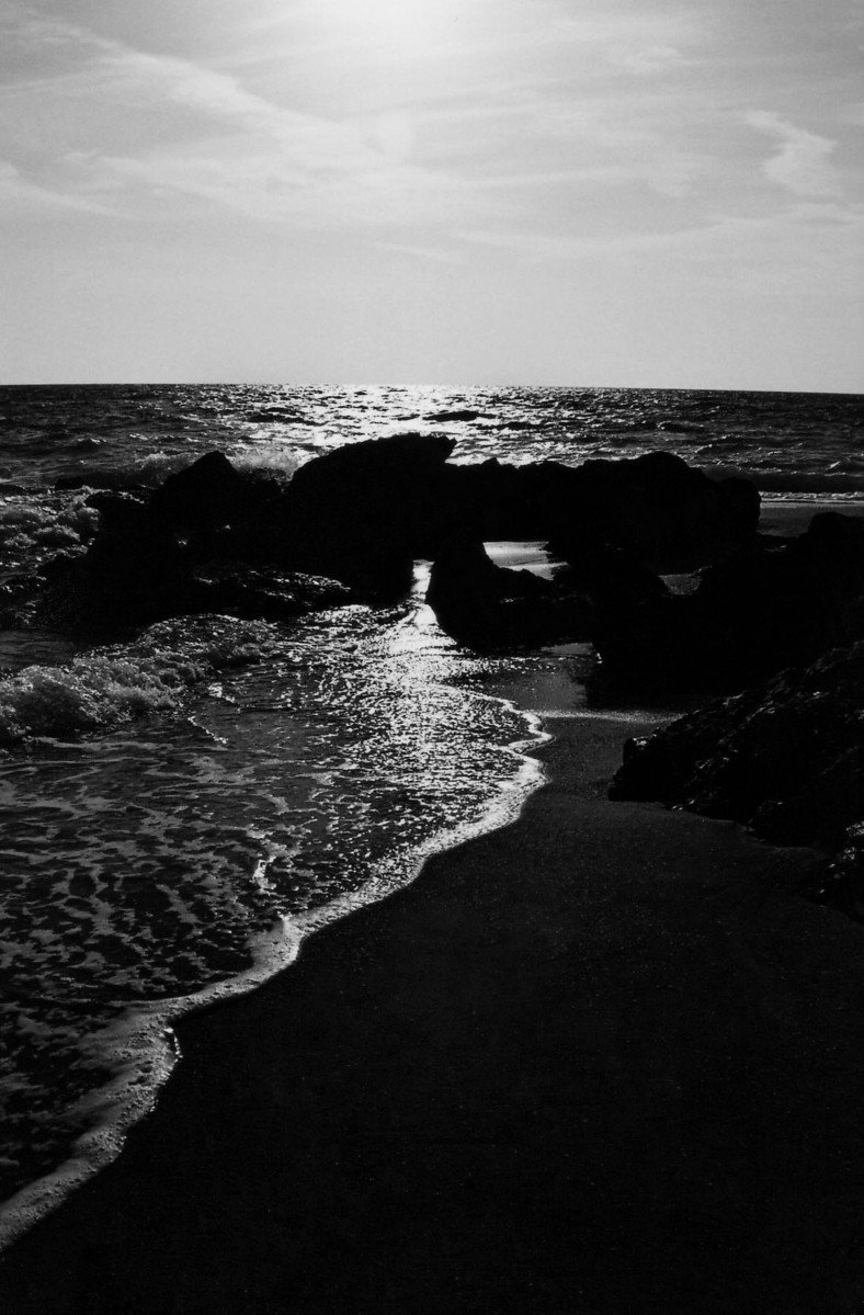 a black and white po of water crashing onto a beach