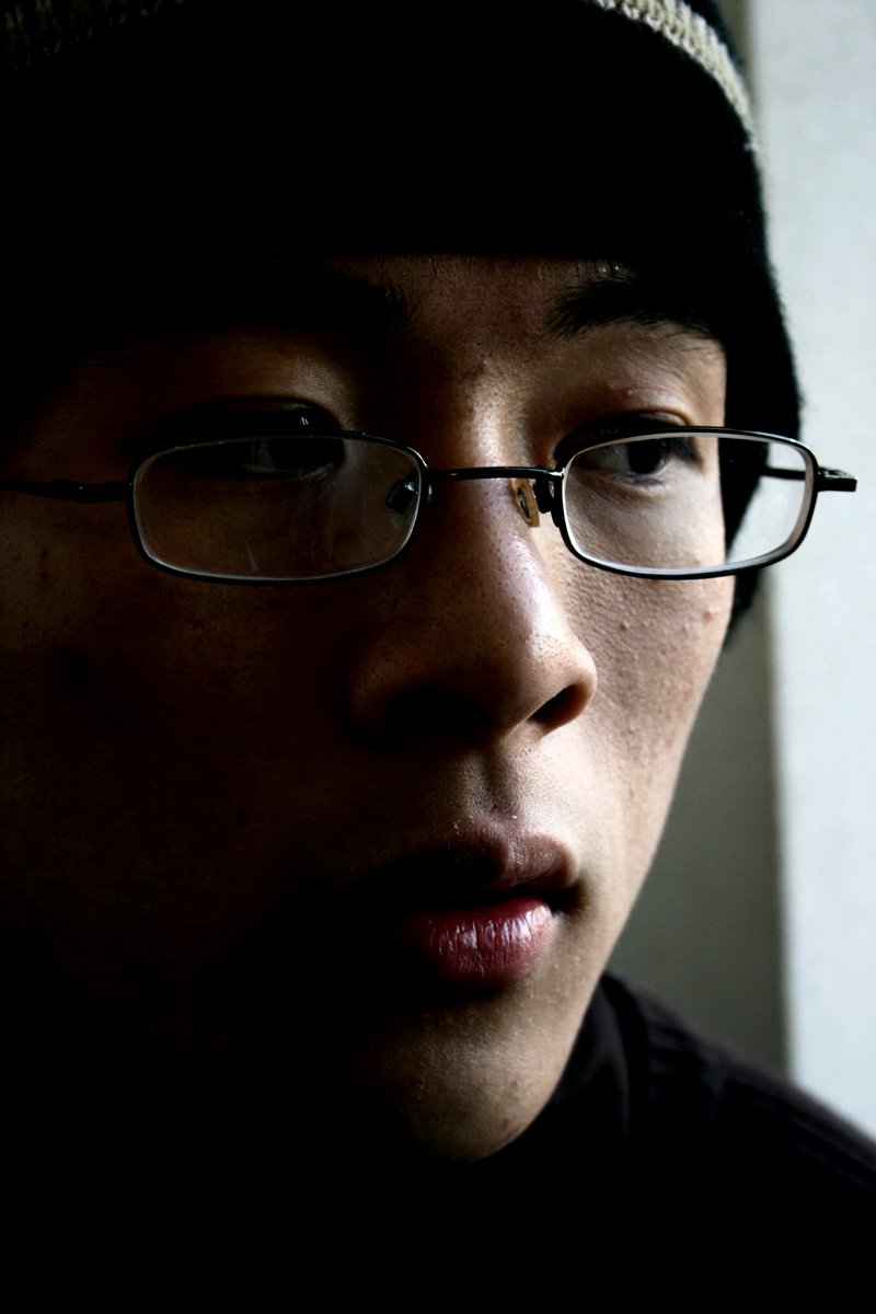 a young man with glasses in a dark room