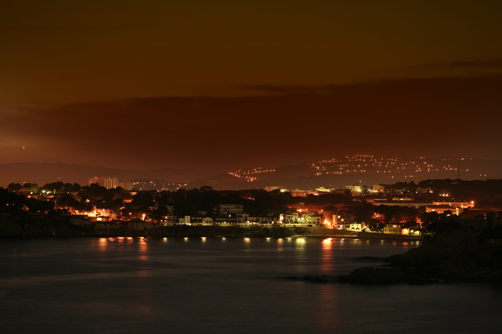 a view of the city lights at night from across the lake