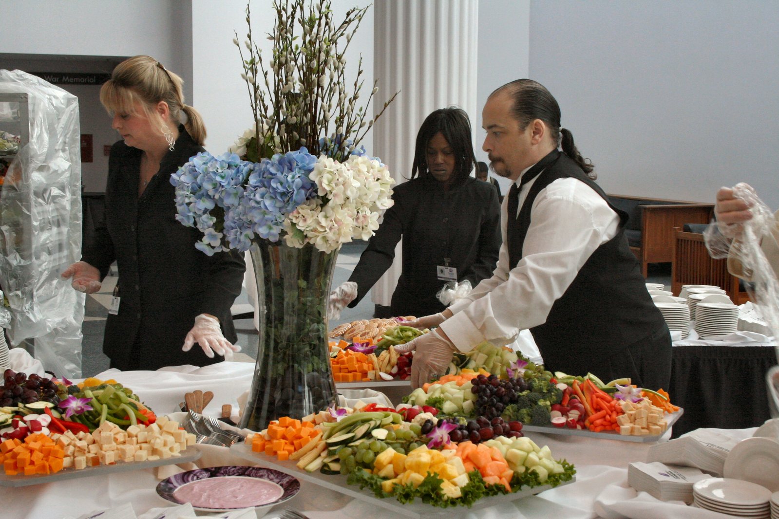 a waiter prepares an arrangement of fresh fruit and vegetables on the table