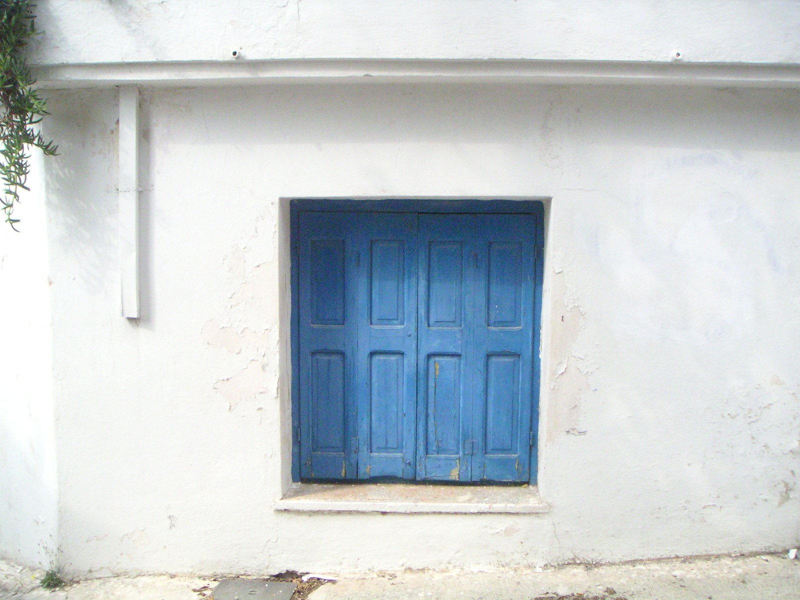 the blue door of an old building has a narrow window
