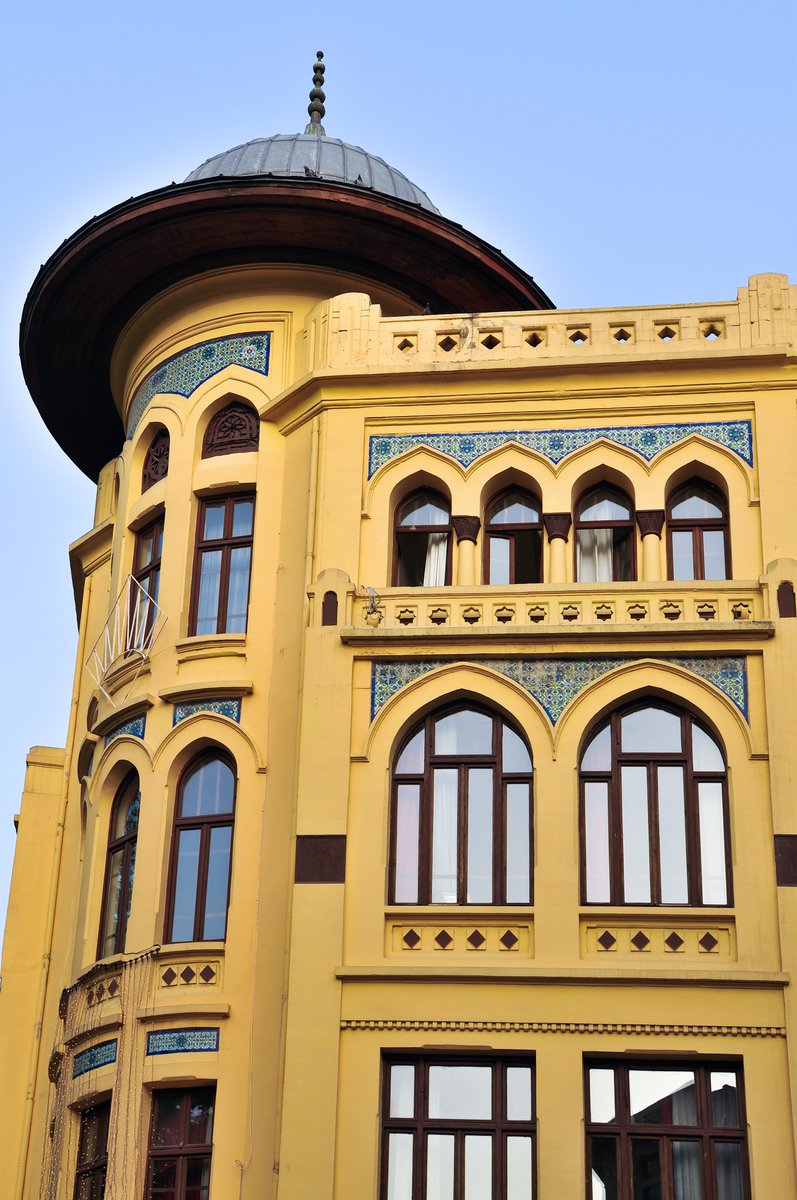 an old looking building that is painted yellow and has some small round windows