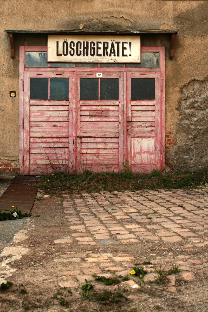 a weathered red door sitting next to a building