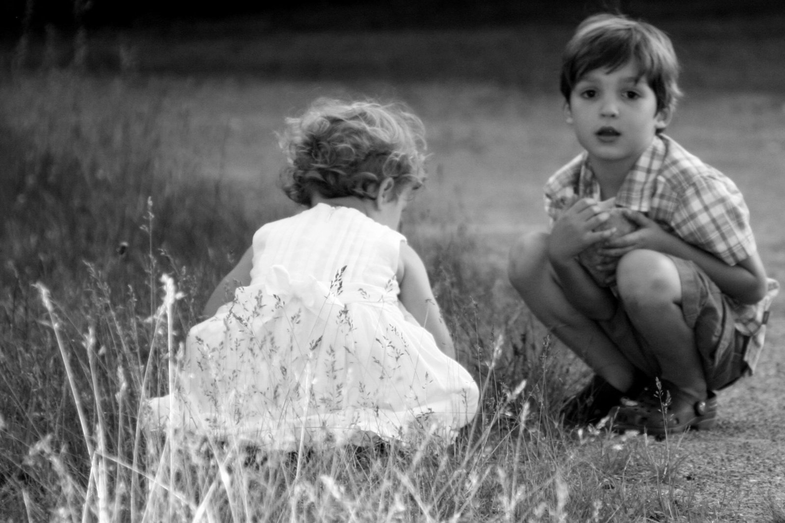 two small children sitting in the grass playing