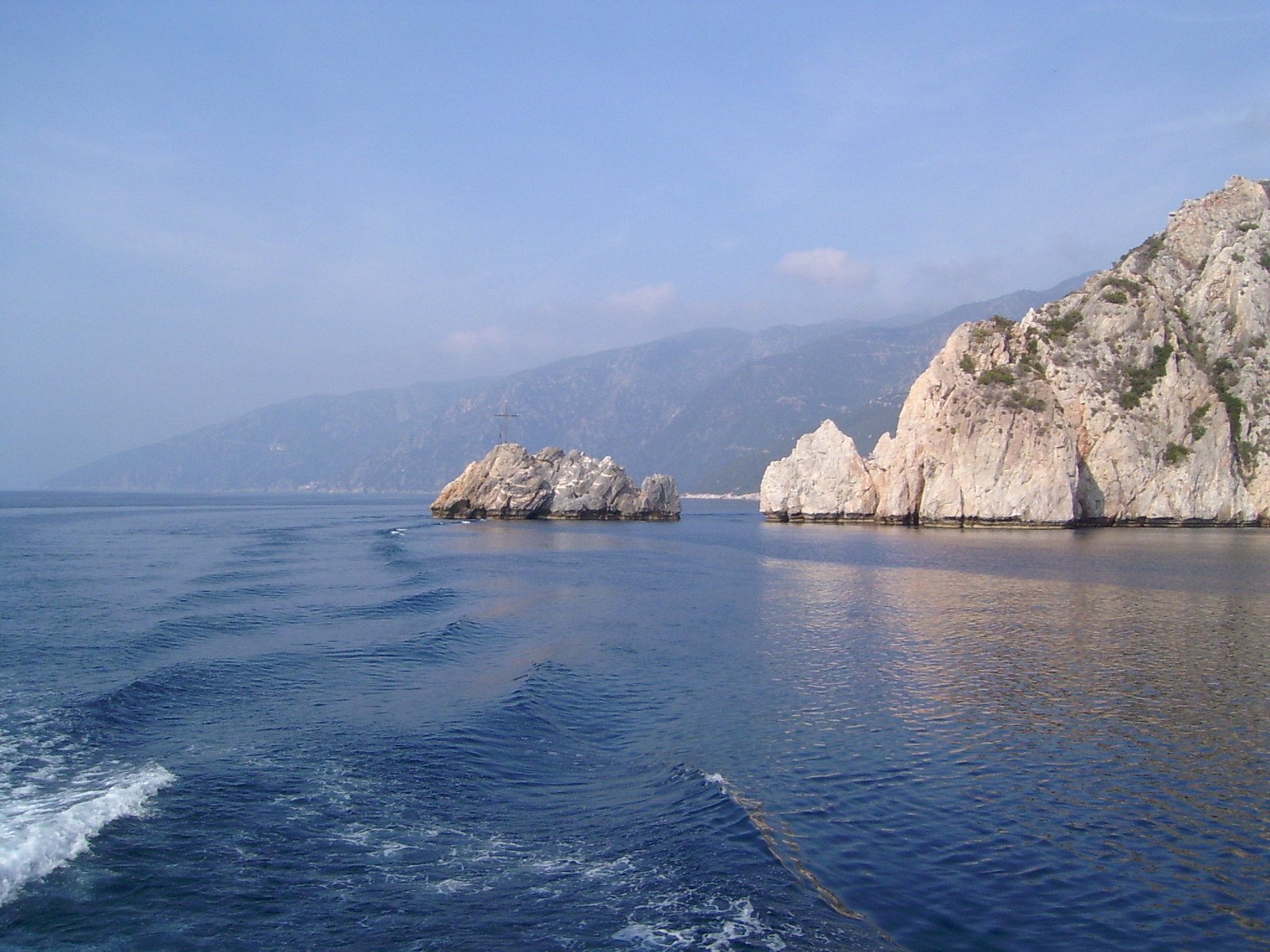 rocks in the ocean and mountains behind them