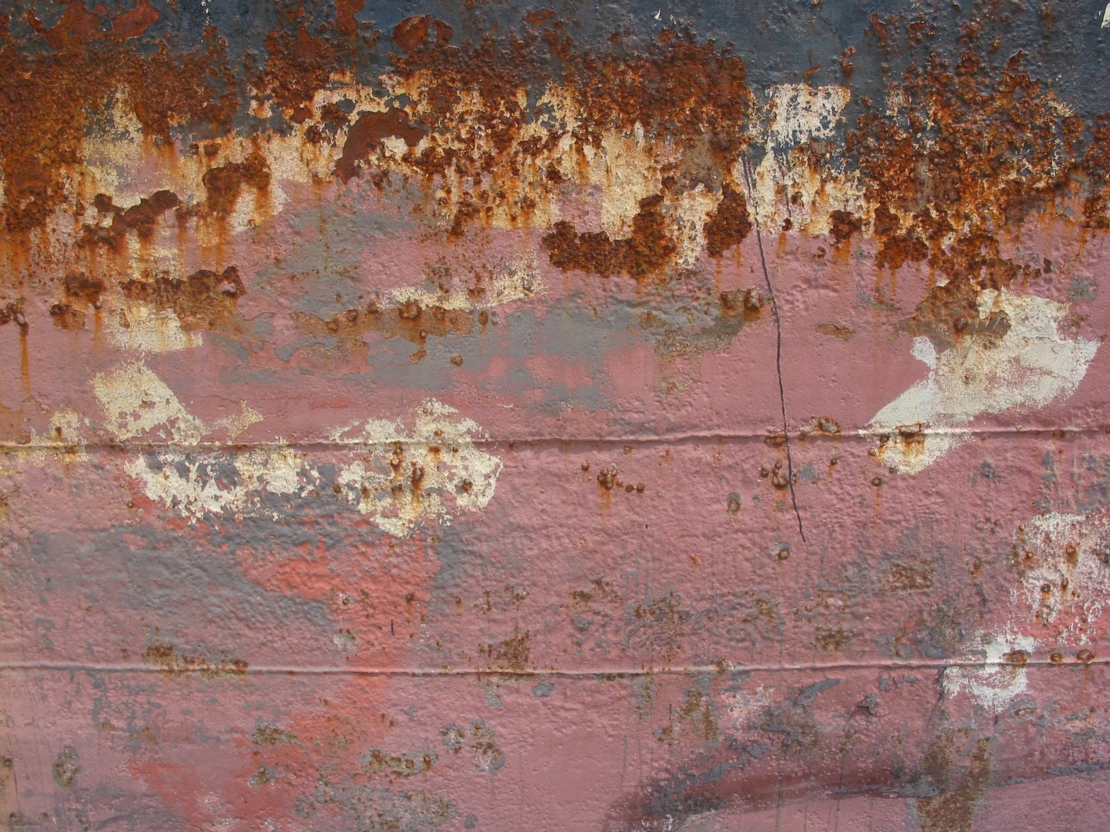 the rusted pink surface is covered by grey, yellow and red paint