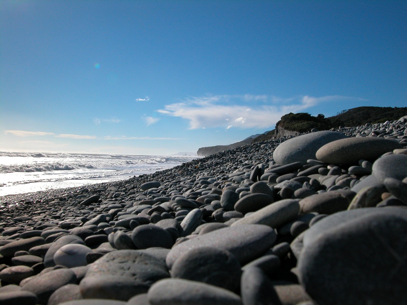 rocks are laying on the shore line with ocean in the background