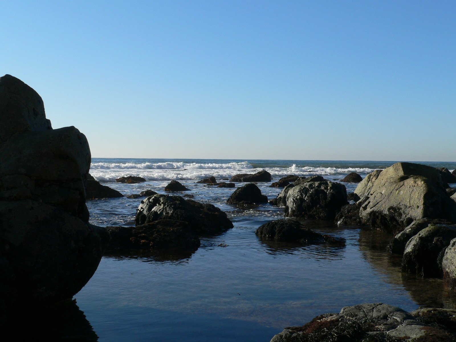a beach with many large rocks near the ocean