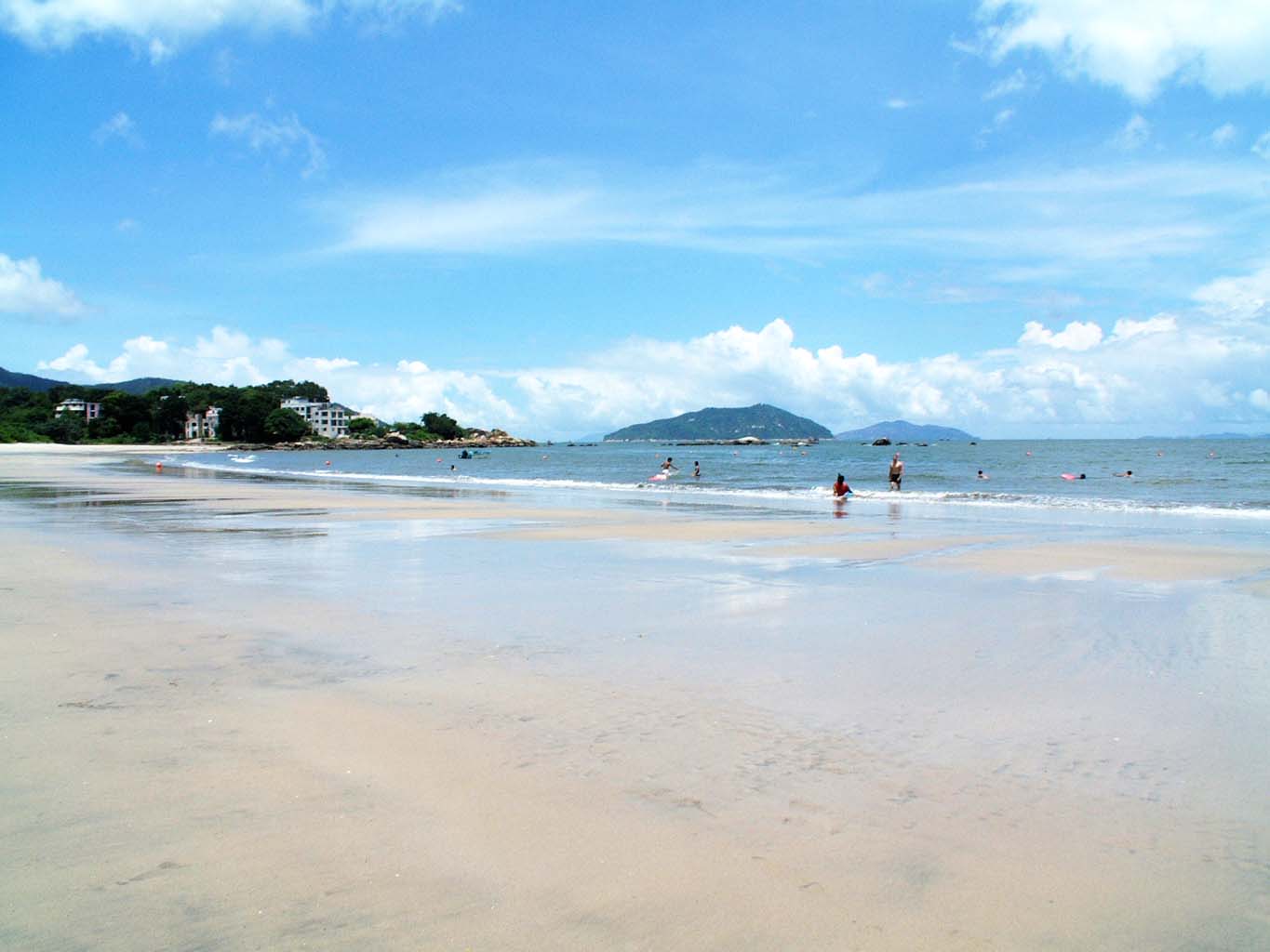 two people are walking in the sand at the beach