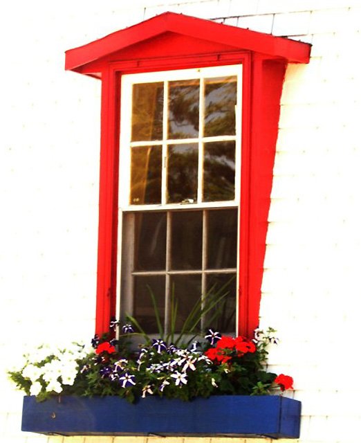 a small red building with flowers in the window