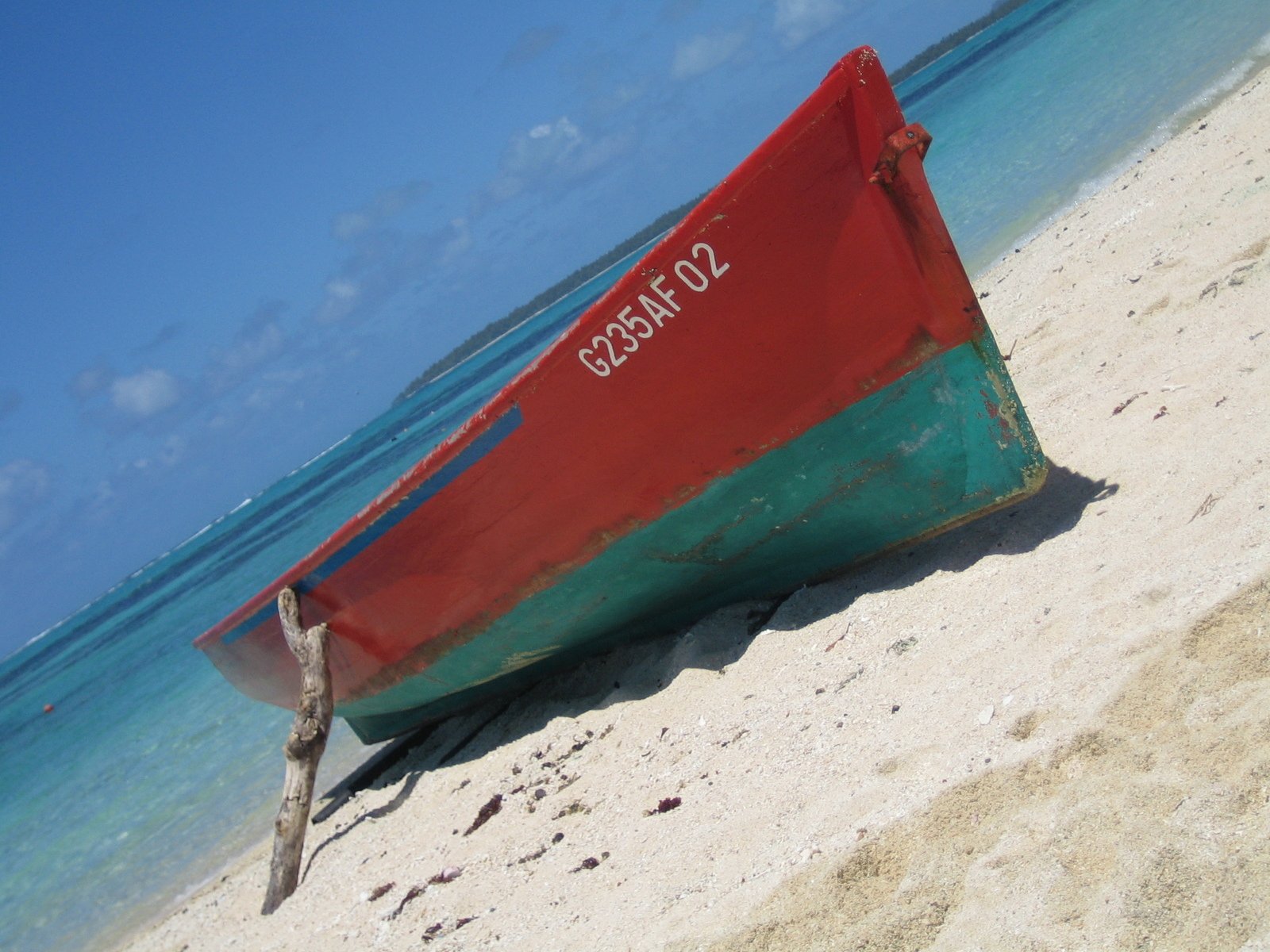 a red boat in the sand near a body of water