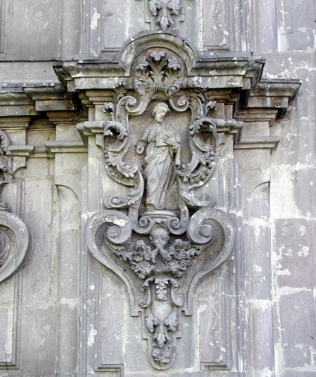 a decorative figure in grey and a clock on top of a wall