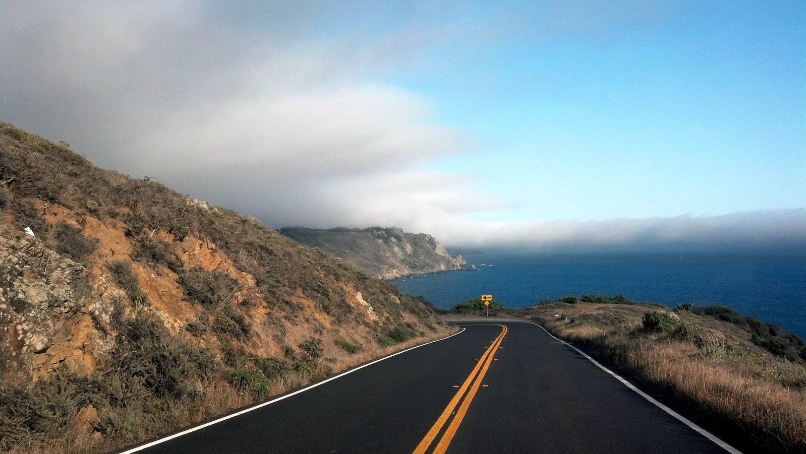 the car is driving down the highway towards the ocean