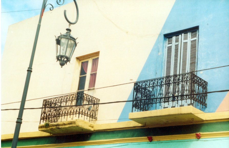 two buildings with iron balconies on either side of the window