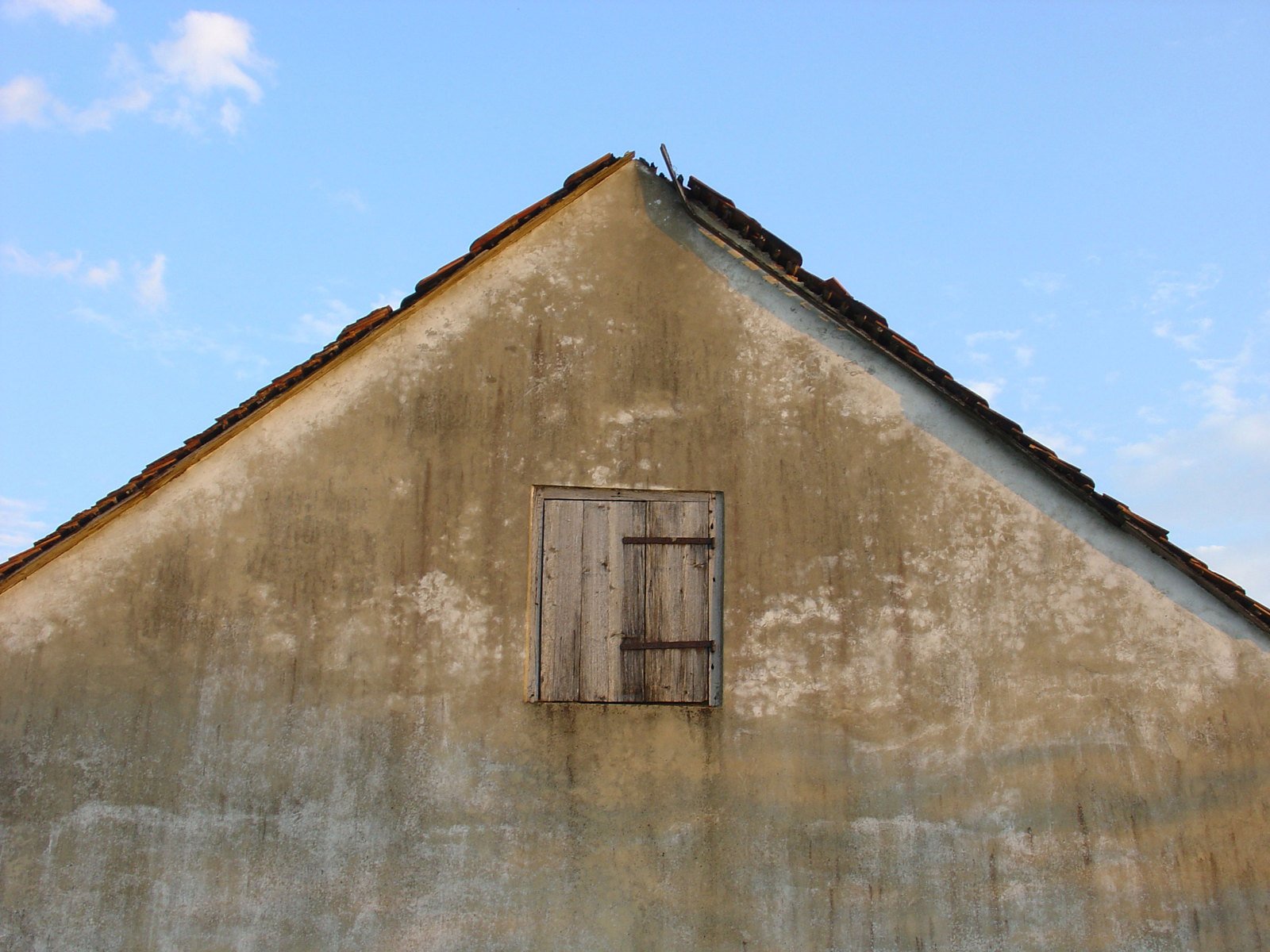 a window in a tan building with a sky background