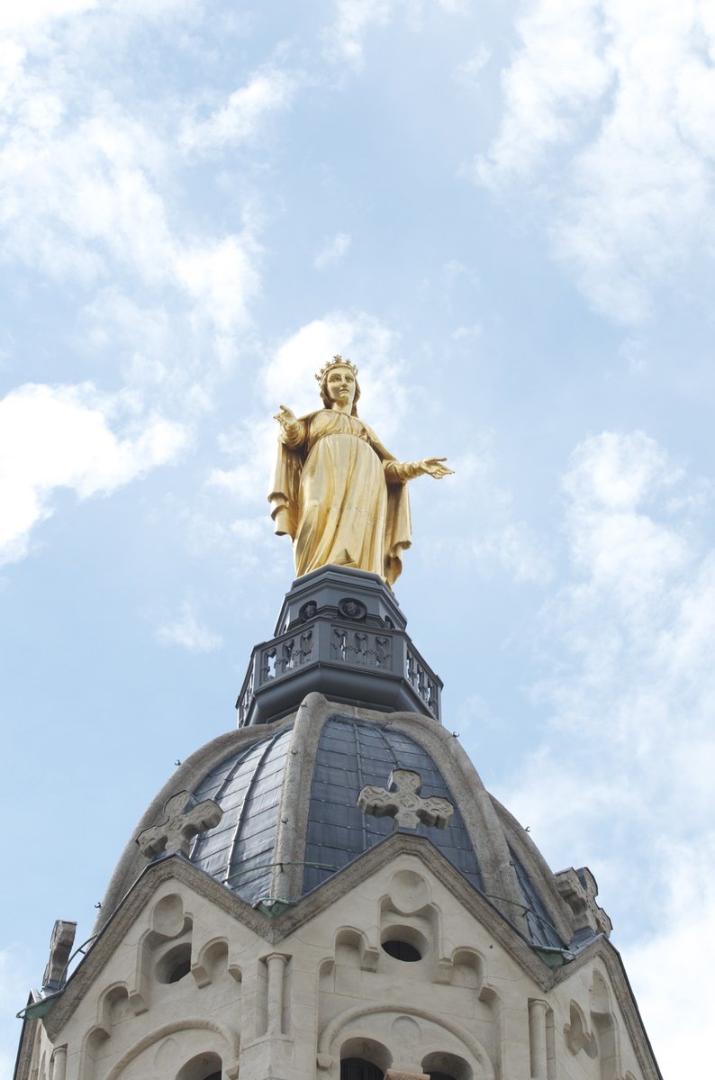 a tall clock tower with a golden statue on top