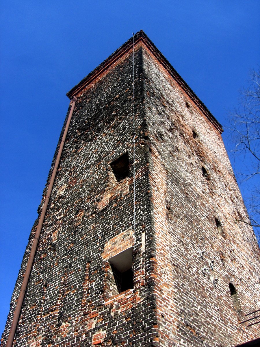 the back side of a brick building with holes in the roof