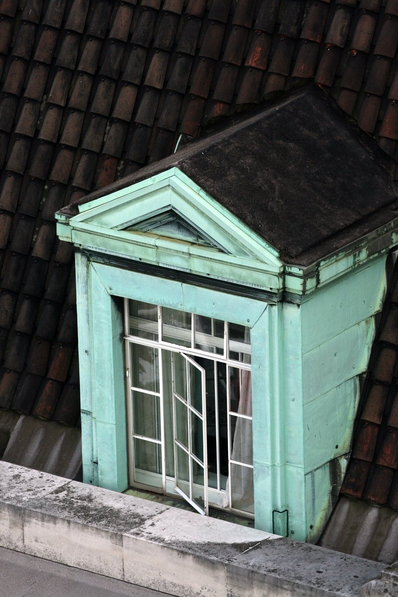 a window sits open near a brown brick roof