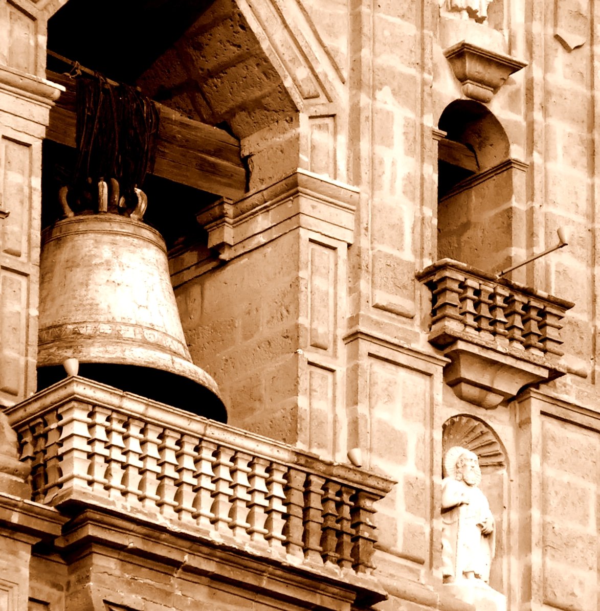 a bell stands outside a building on top of the tower