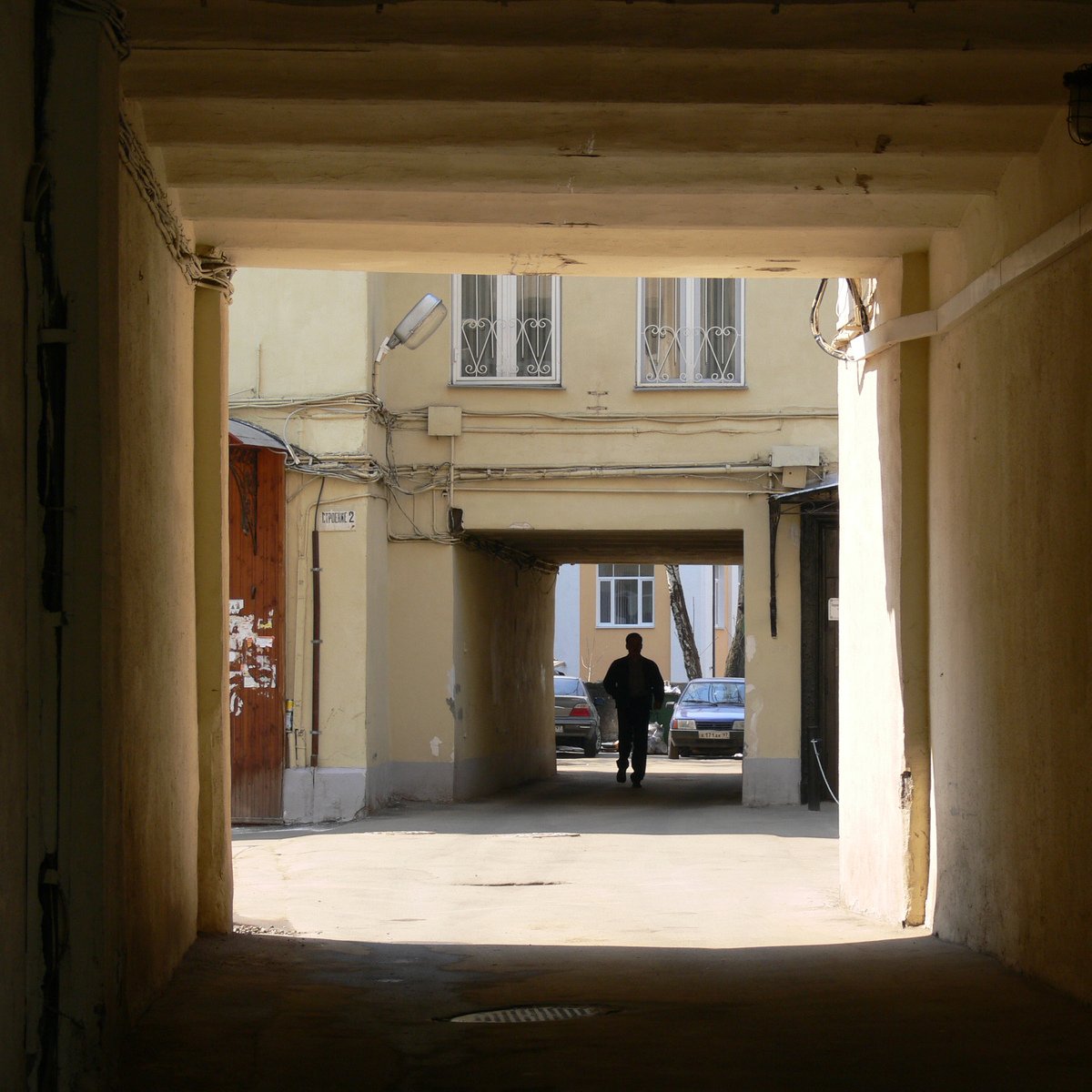 a man is standing by himself near an overhanged entrance to a large building