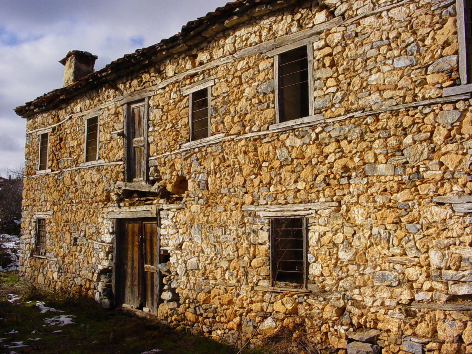 an old, stoned house with broken windows in an old country setting
