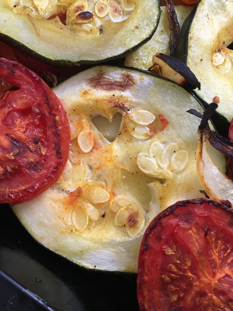 the food on this dish is cooked and has tomato and peppers on it