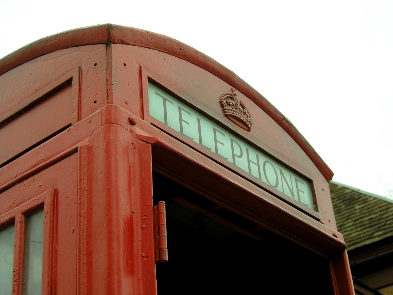 an old fashioned red phone booth with a sign in front of it