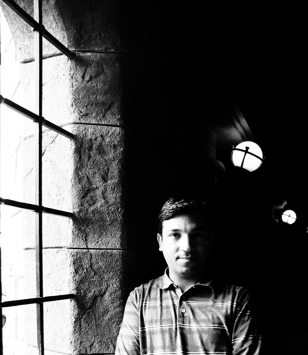 black and white image of a man sitting down looking out a window