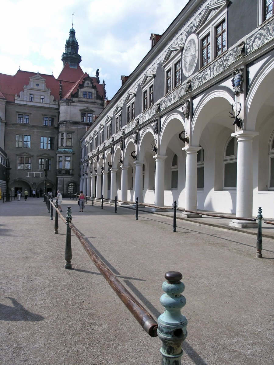 a large white building with arches and a green gate
