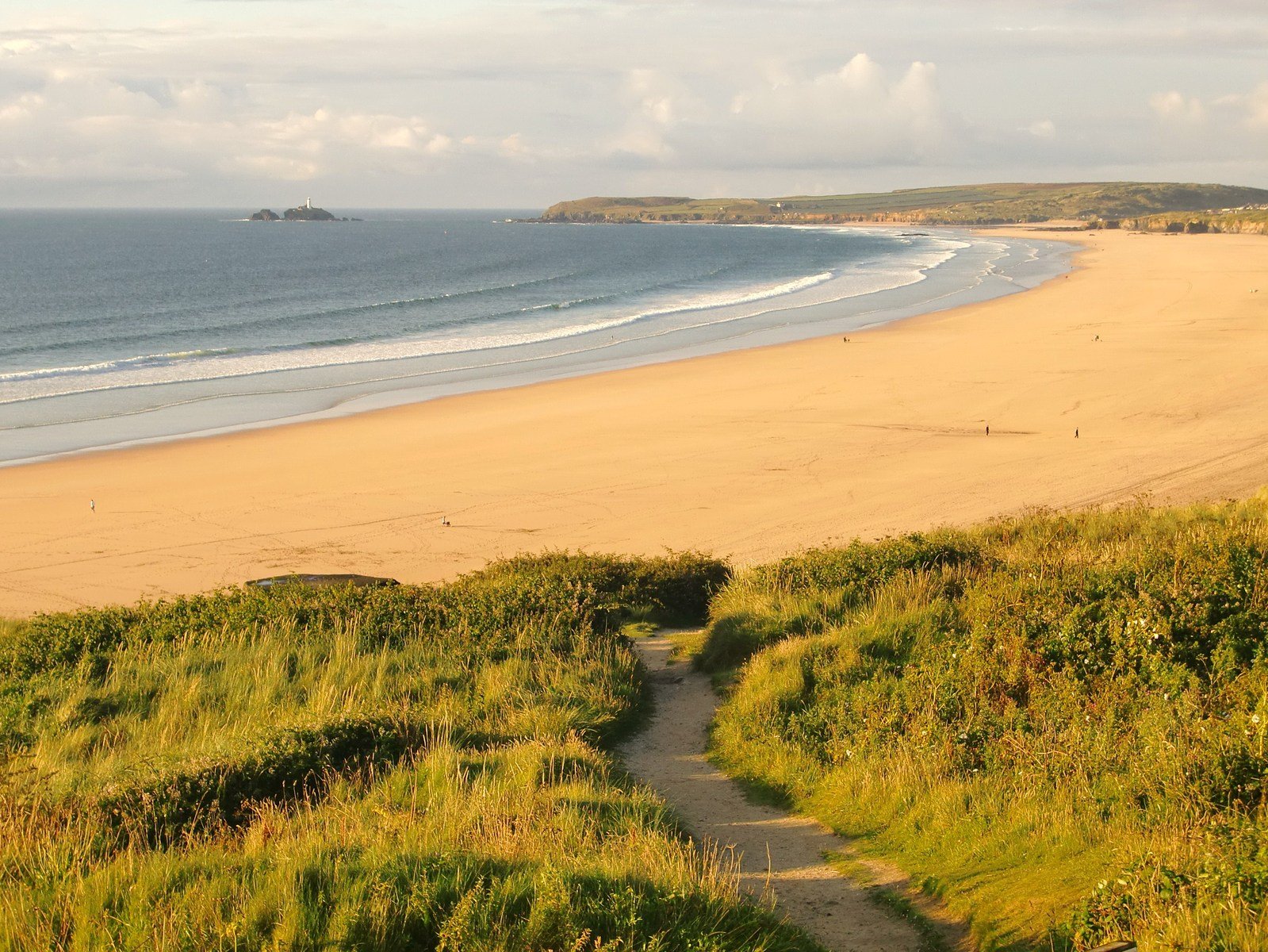 a narrow path leads up towards the beach from the top of a hill