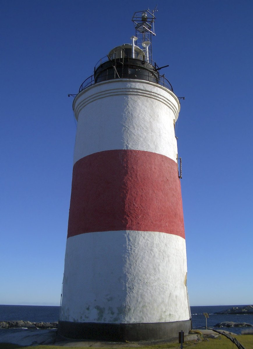 the large white and red lighthouse is near a body of water