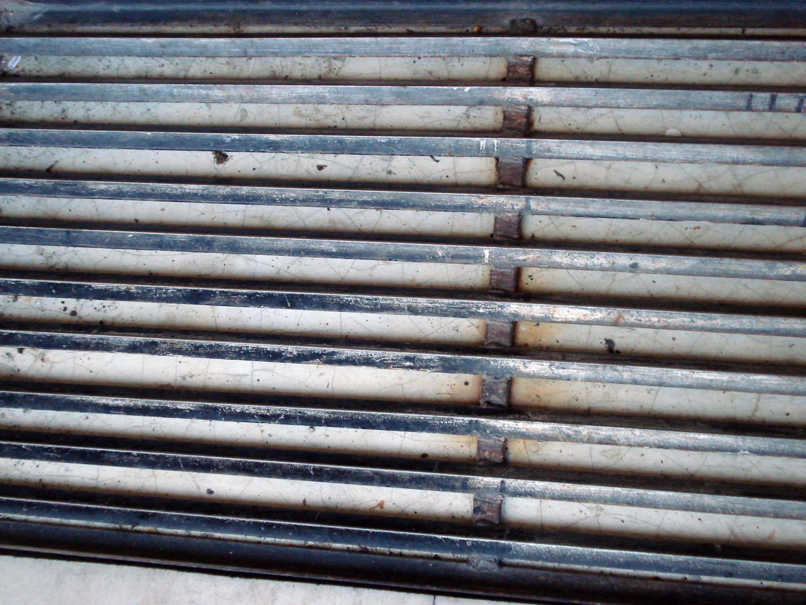 the front side of a white, weathered metal building with a stack of pipes next to it