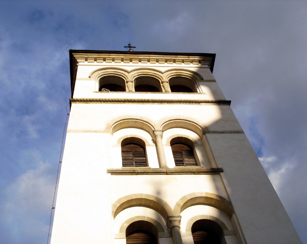 a tall clock tower with three windows under a blue cloudy sky