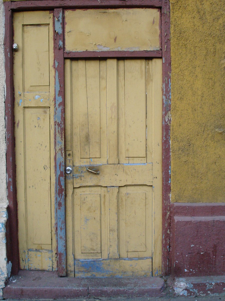 an old wooden door next to a crumbling wall