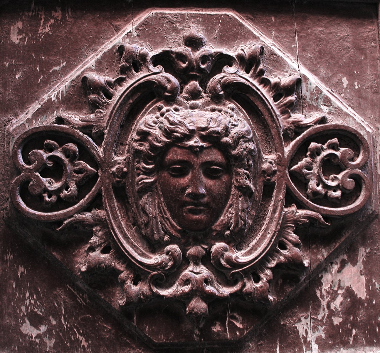 ornate face carving on old door in urban setting