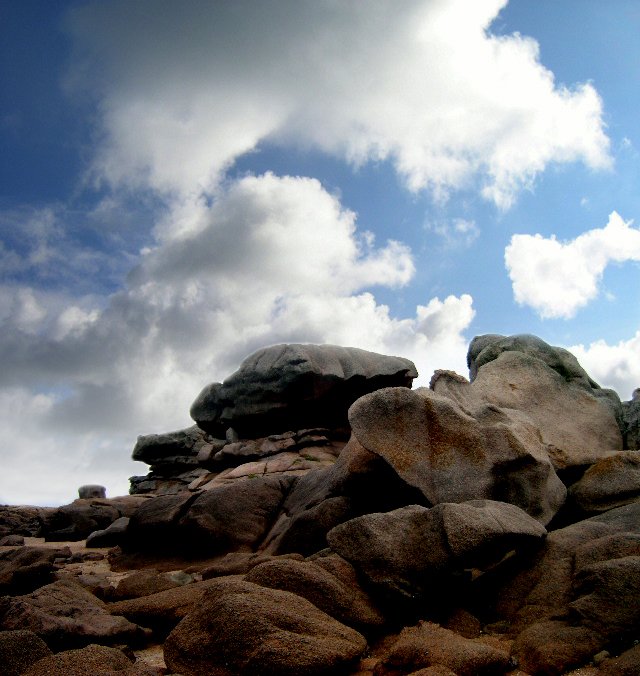 rocks under a blue cloudy sky on a beach